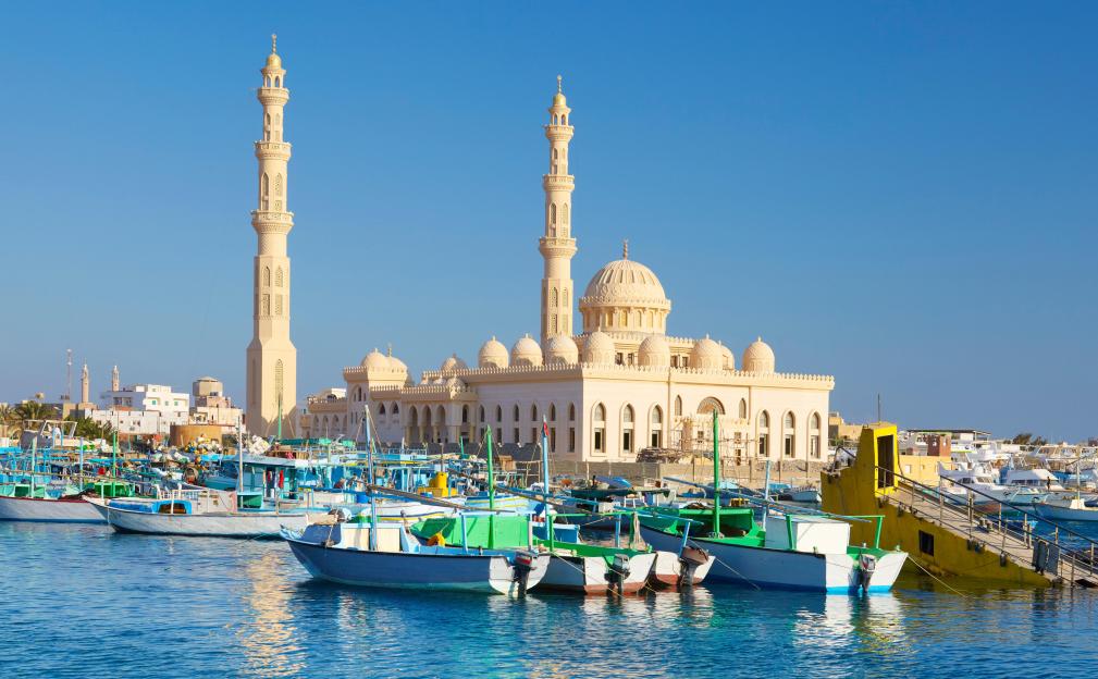 Marina with boats in the foreground and a large mosque with two minarets in the background in Hurghada, Egypt.