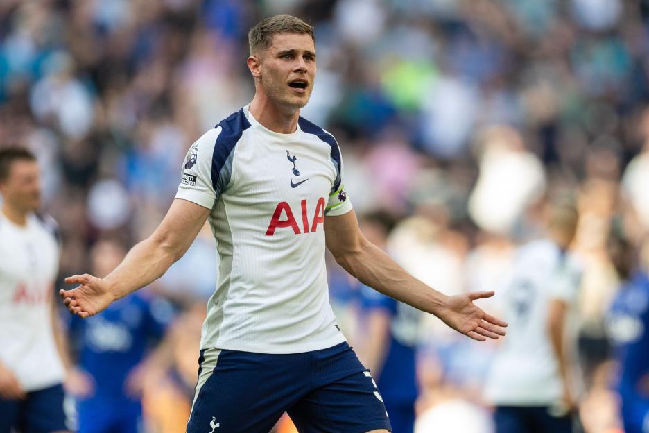 Footballer in a white and blue uniform with arms outstretched, looking exasperated.