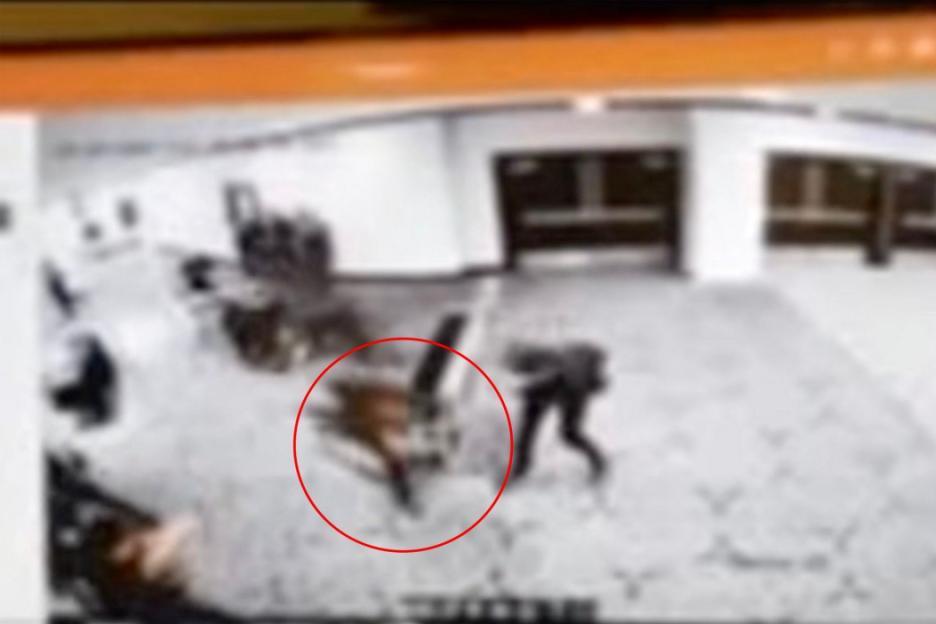 Blurred security footage showing a person crawling and another person or object within a red circle during a chaotic scene.