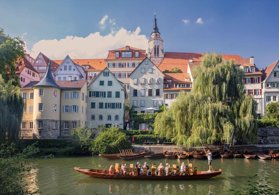 Punting boat on the Neckar River with the Collegiate Church and Hölderlin tower in the background, Tübingen, Germany.