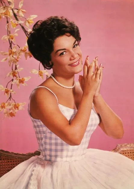 Studio portrait of American singer Connie Francis wearing a lavender and white spaghetti-strap dress.