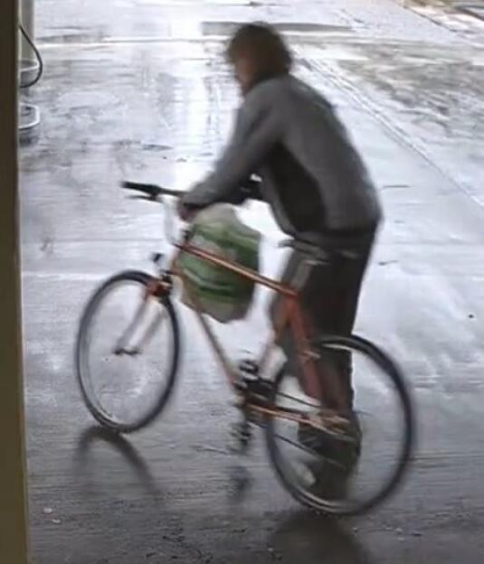Person on a bicycle, viewed from the side, on a wet or reflective surface.
