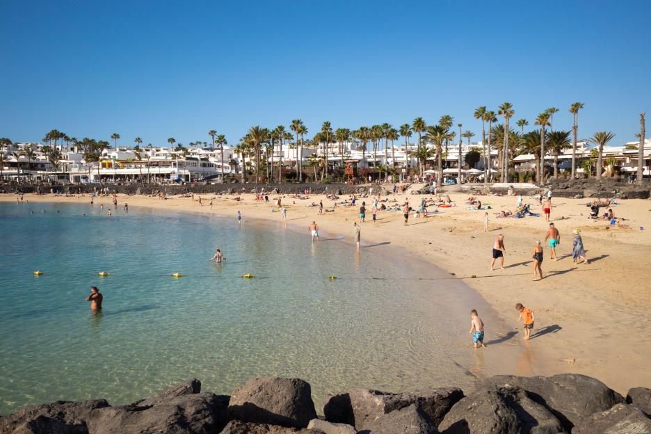 Beachgoers at Playa Flamingo beach in Playa Blanca, Lanzarote, Canary Islands, Spain.