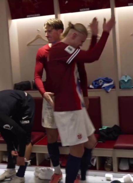 Erling Haaland celebrating with a teammate in a locker room.