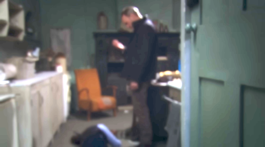 A man standing over a person lying on the floor in a room.