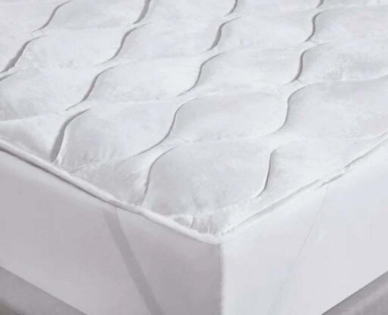 White plush mattress topper on a bed.