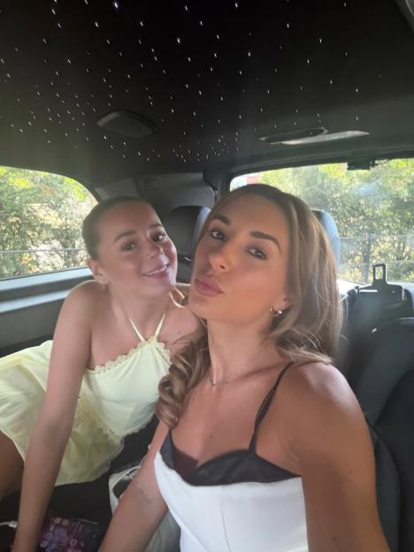Dani Dyer and another woman posing in a car with a "starlight" ceiling.