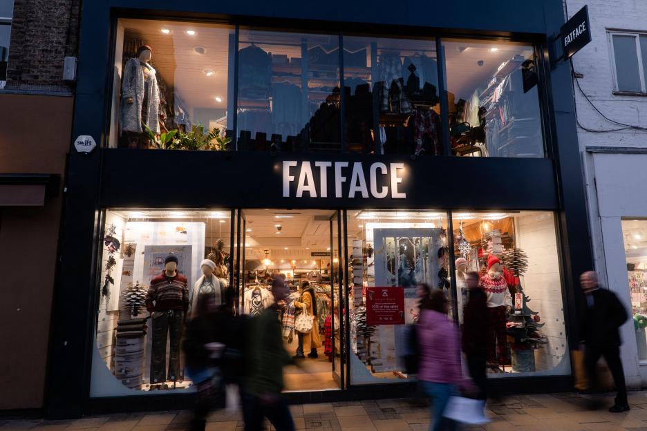 A customer at a boutique fashion store hands over an item of clothing to the cashier at the checkout counter.