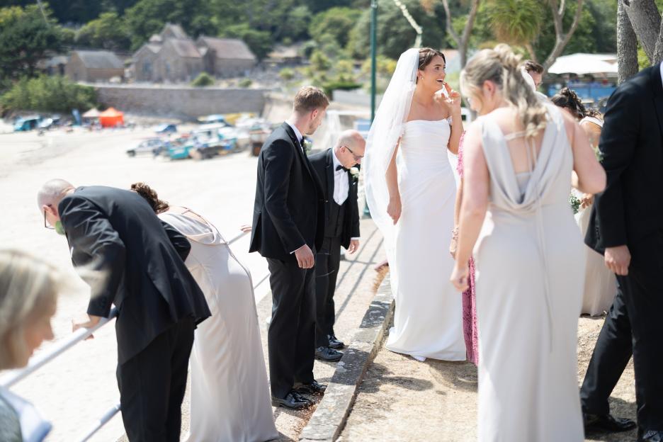 Wedding guests searching for the bride's lost ring on a beach.