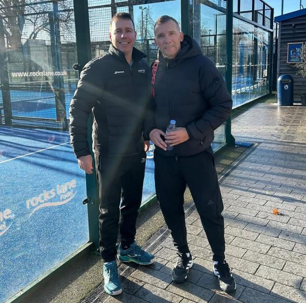 Andriy Shevchenko stands on a padel court with another man.