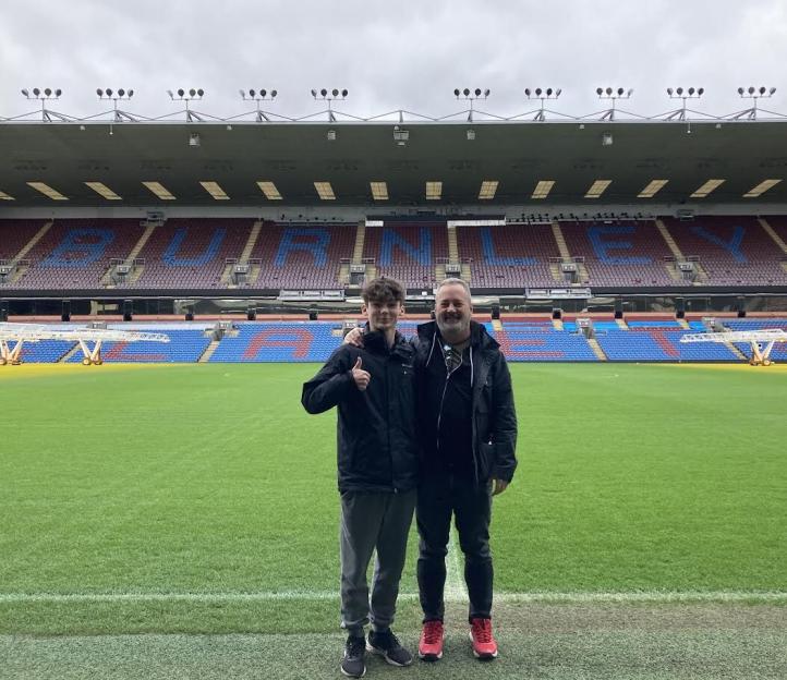 Chris Jones and Sammy standing on the field of Turf Moor stadium.