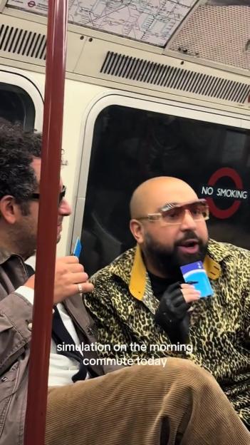 A man in sunglasses and a leopard print jacket rants on a subway train while holding a blue card.