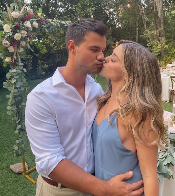 Taylor Lautner kissing Tay Dome with a floral arch in the background.