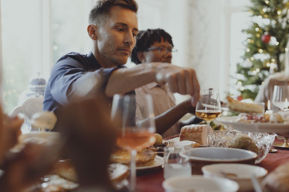Man serving food at a Christmas dinner table.