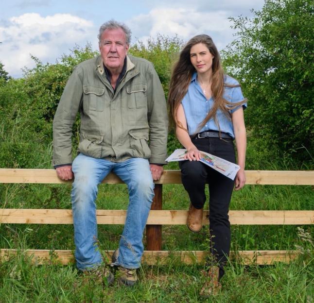 Jeremy Clarkson and Hannah Bourne-Taylor sitting on a wooden fence.
