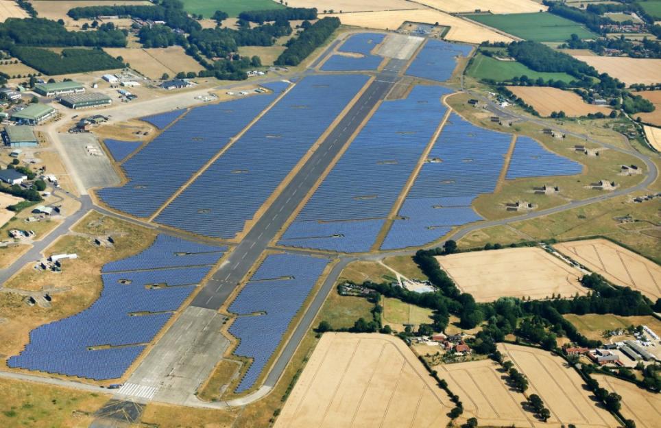 Aerial view of a large solar farm built around an airfield with runways.