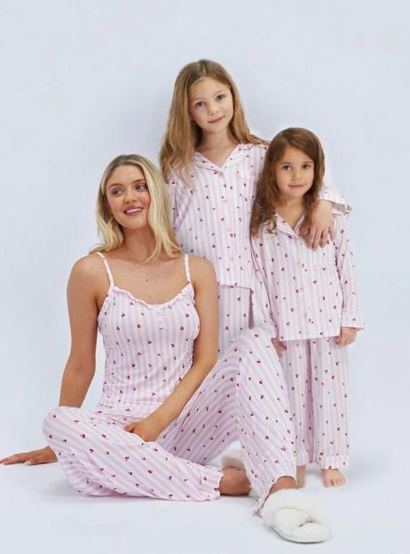 A woman and two young girls in matching pink and white striped pajamas with strawberry prints.