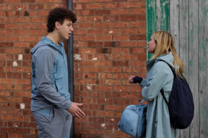 A young man and woman talking with duffel bags and backpacks.