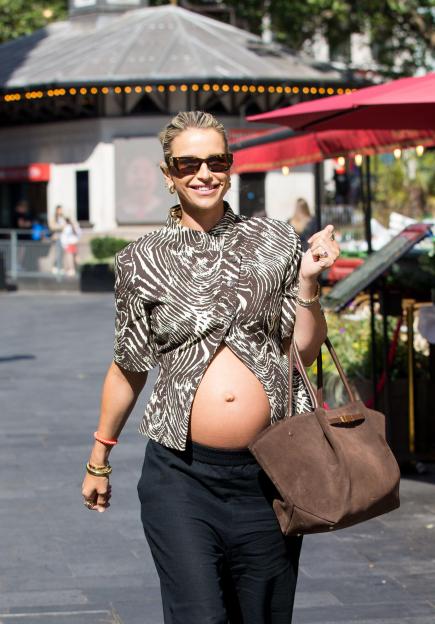 Vogue Williams in a zebra print top revealing her baby bump, black trousers, and sunglasses.
