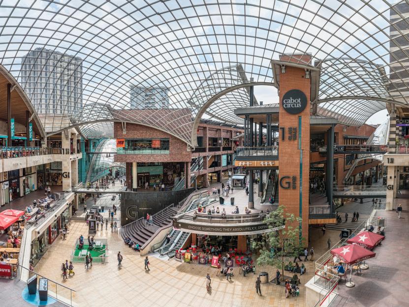 Cabot Circus Shopping Centre in Bristol, England, with multiple levels of stores and restaurants under a large glass roof.