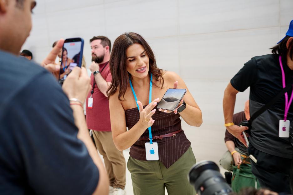 A woman demonstrates Apple's foldable iPhone Duo to attendees at a special event.