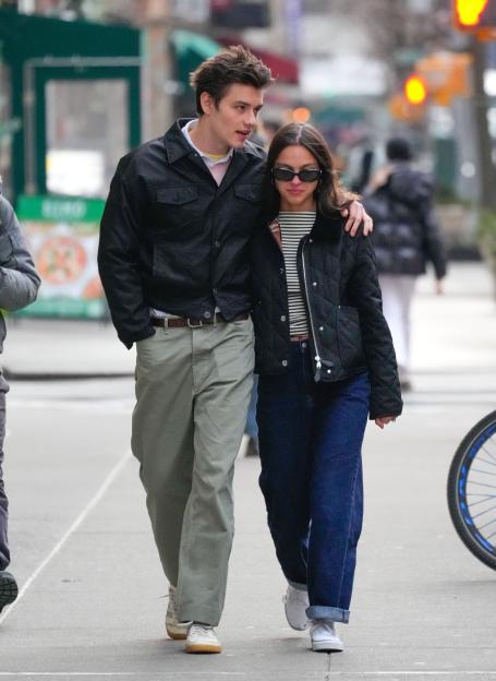 Olivia Rodrigo and Louis Partridge walking down a city street.