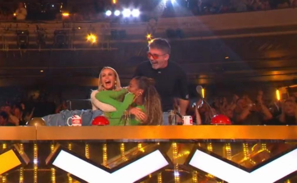 Two judges celebrate by jumping for the golden buzzer, with a third judge cheering with a raised fist.