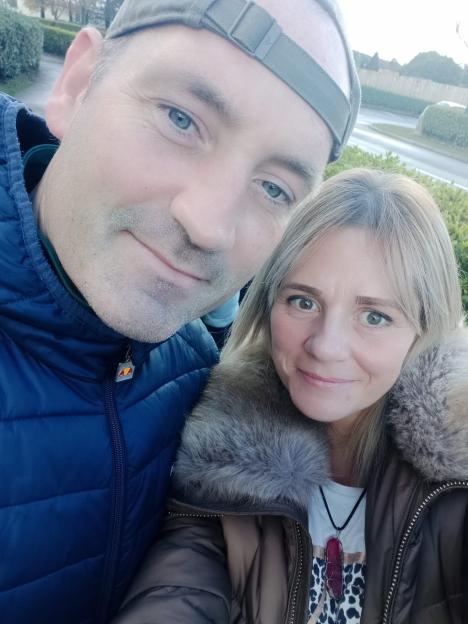 Selfie of a man and a woman smiling at the camera outdoors.