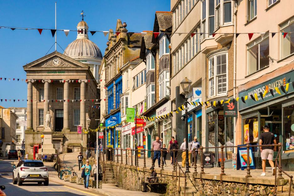 Market Jew Street in Penzance, Cornwall, with a busy main shopping area on a sunny spring day.