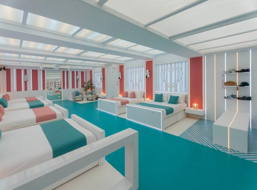 Brightly lit bedroom with multiple beds, teal flooring, and pink accents.