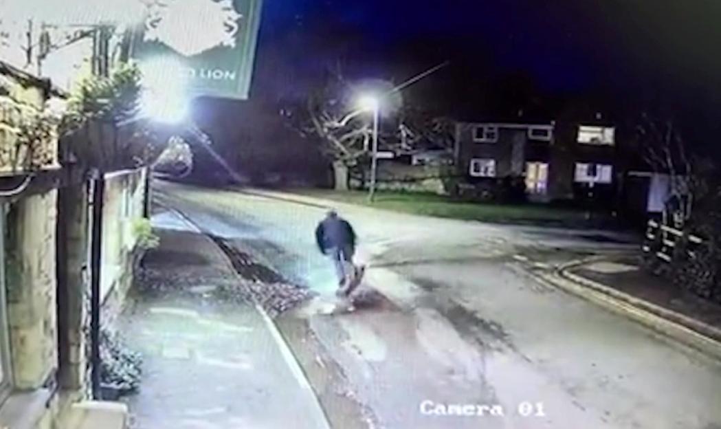 CCTV footage of an e-scooter rider hitting a pothole and falling on the road outside a pub at night.