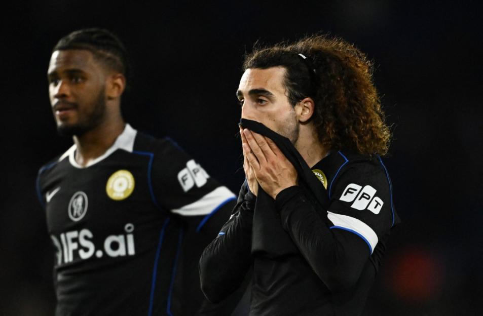 Brighton & Hove Albion player Marc Cucurella covers his mouth in dismay, with teammate Tariq Lamptey looking on in the background.