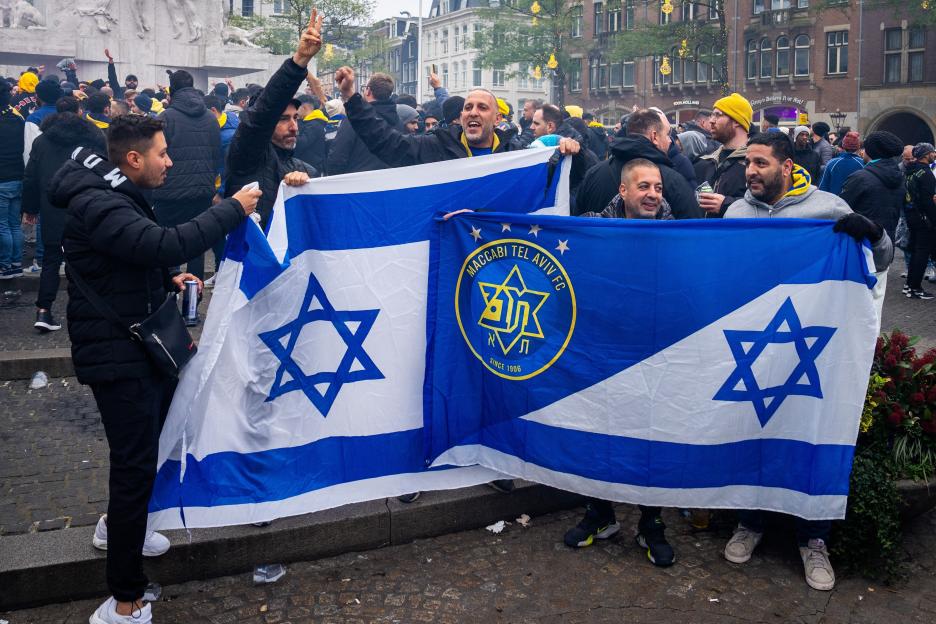 Maccabi Tel Aviv supporters holding an Israeli flag and a team flag.