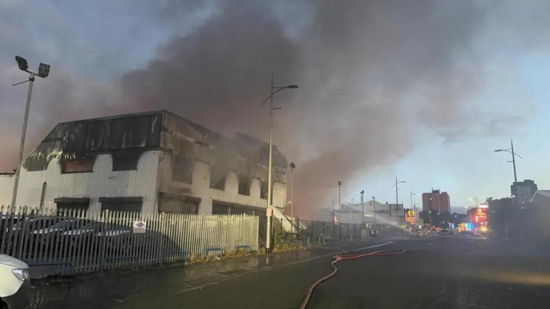 Smoke rises from a burning commercial building on Bury New Road in Salford.
