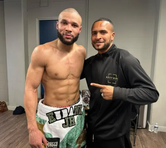 Two men posing for a photo, one shirtless and the other in a black jacket.