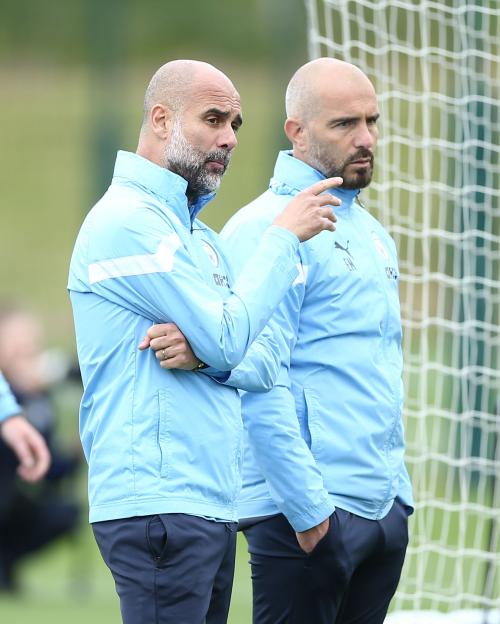 Manchester City manager Pep Guardiola speaking to assistant manager Enzo Maresca during a training session.
