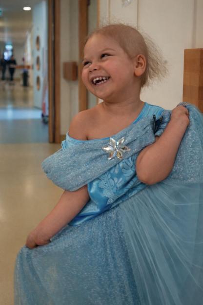Primrose Hocking in a blue dress with a snowflake brooch, laughing.