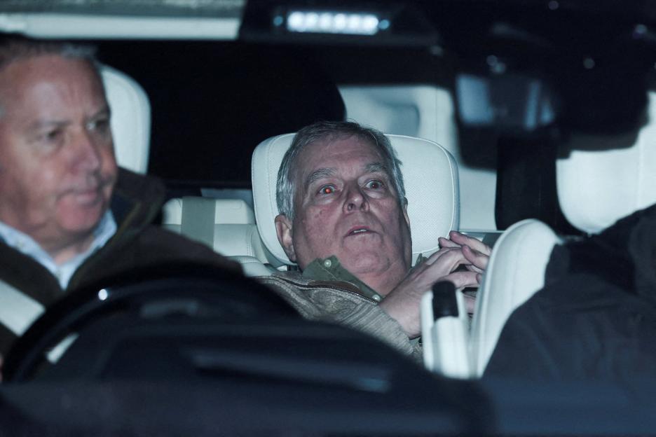 Andrew Mountbatten Windsor, formerly Prince Andrew, sits in a car, looking surprised or shocked, with another man blurred in the foreground.