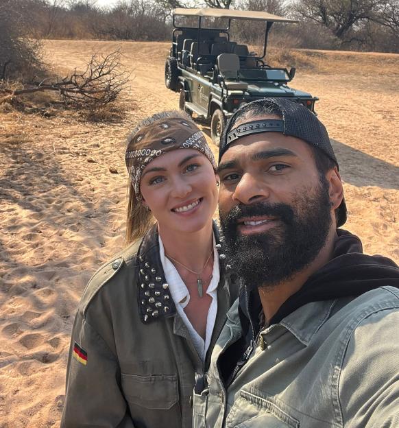 David Haye and girlfriend Sian Osborne taking a selfie in front of a safari vehicle in a dry, sandy landscape.