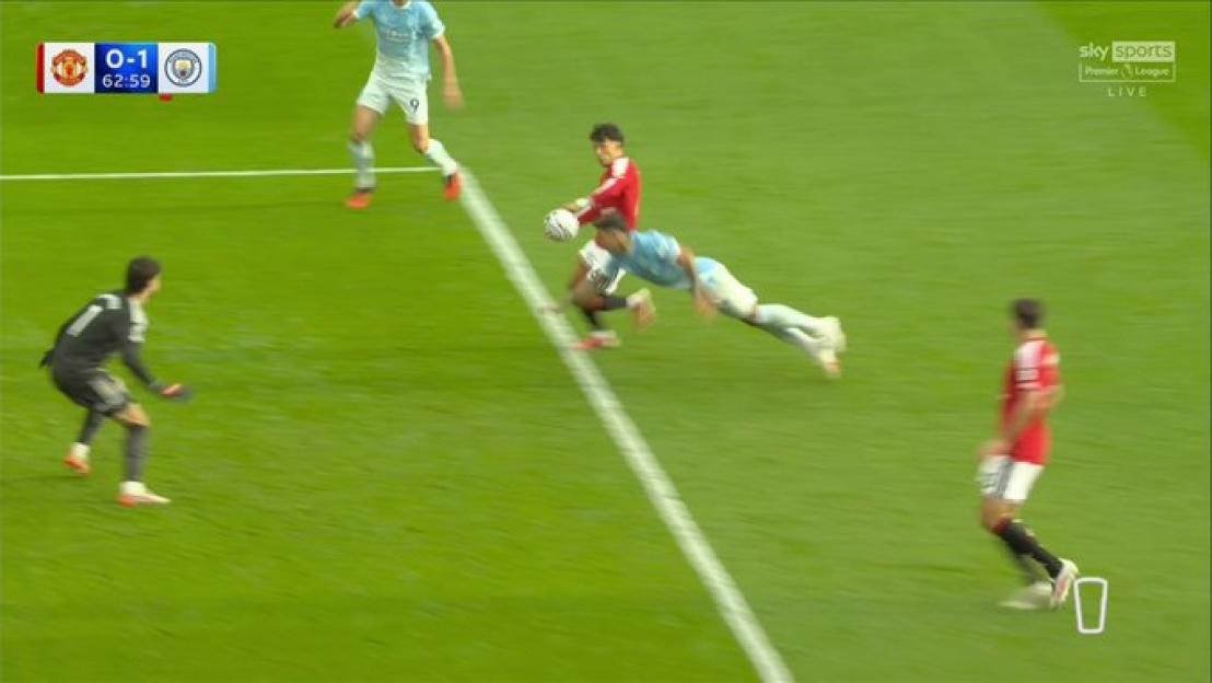 Soccer players from Manchester United and Manchester City competing for the ball on the field, with the scoreboard showing Manchester United 0 - Manchester City 1.