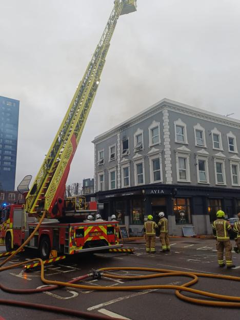 Firefighters with a ladder truck at a mixed-use building on Battersea Park Road where an incident caused significant traffic disruption.