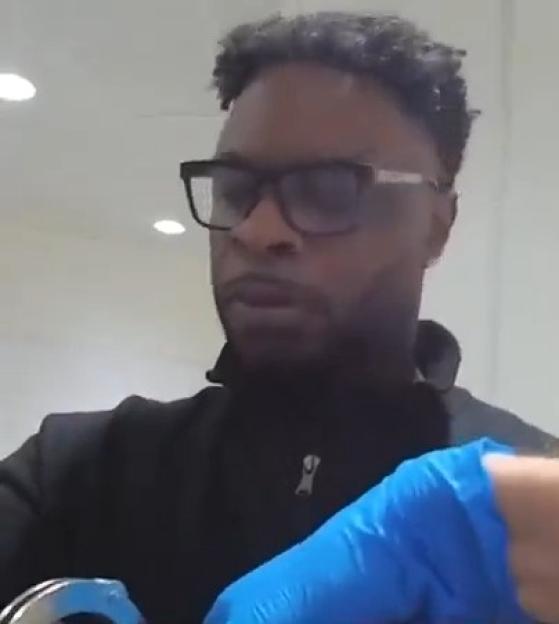 Daniel Brown, wearing glasses, being handcuffed by an officer in blue gloves.