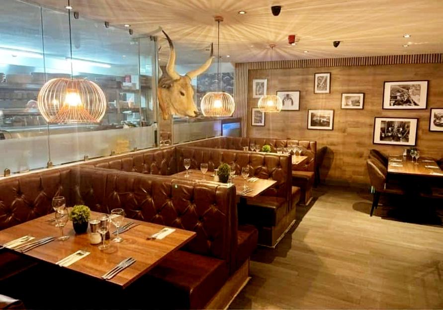 Relentless Steak and Lobster House in Portsmouth with brown booths, wooden tables, and a cow's head decoration.