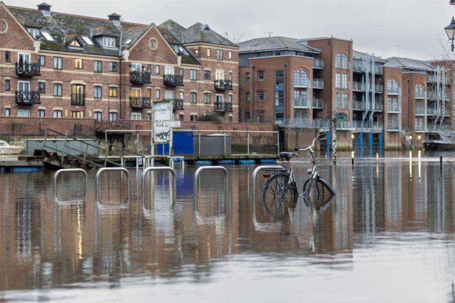 A flooded street in York city centre with a bicycle partially submerged next to a building.