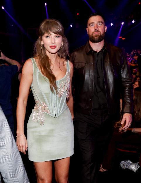 Taylor Swift in a light green mini-dress and Travis Kelce in a dark brown leather jacket at the 2026 iHeartRadio Music Awards.
