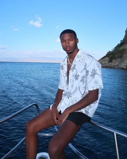 Roman Hackett on a boat with the sea and mountains in the background.