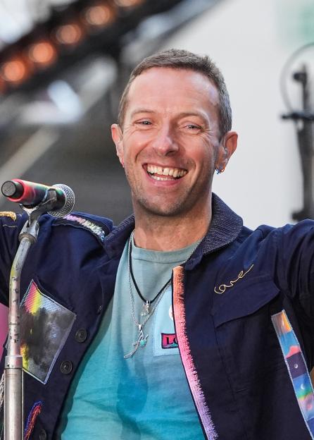 Chris Martin of Coldplay smiling while performing.
