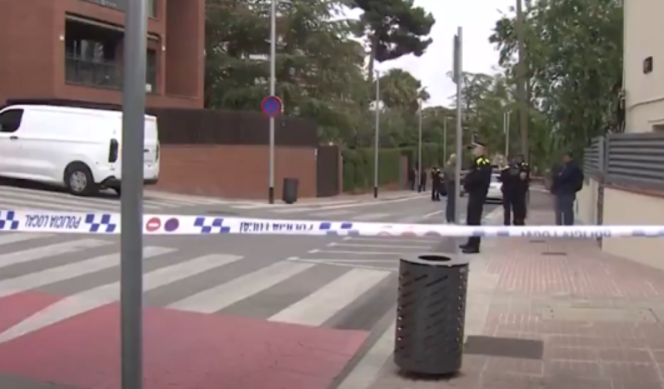 Police tape blocks a street where police officers are gathered in the background.