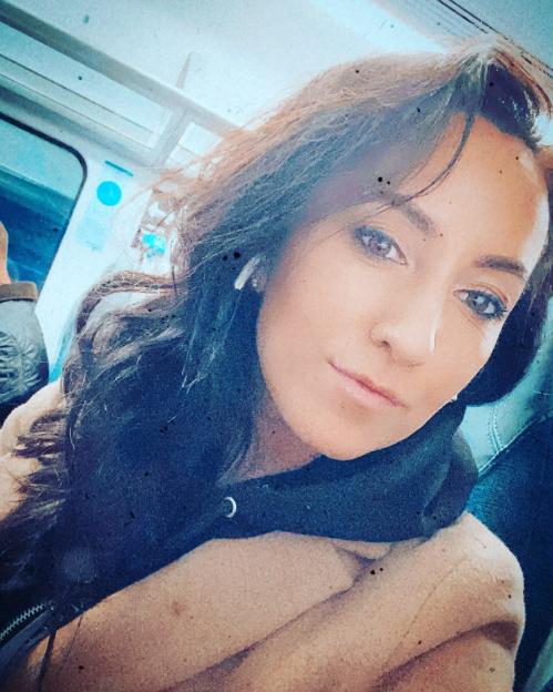 a woman wearing ear buds looks at the camera