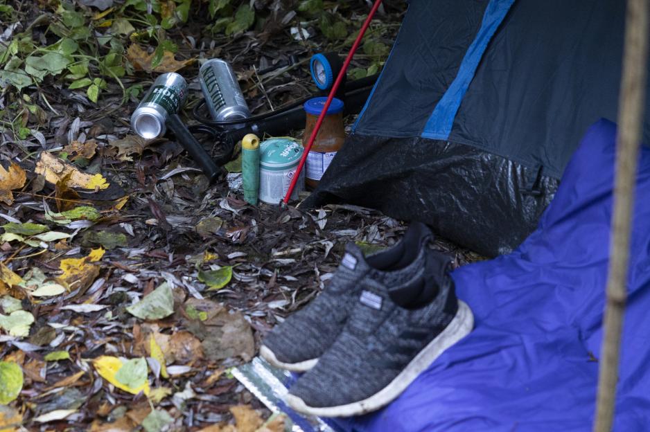 Christian Bruckner's campsite with beer cans, pasta sauce, and trainers outside a tent in Kiel, Germany.